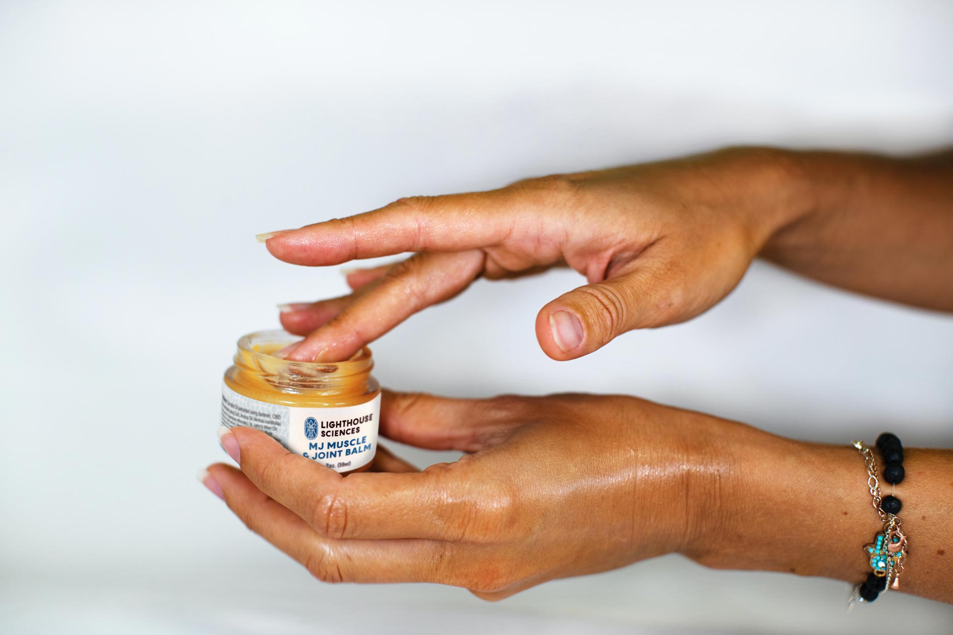 finger dipping into jar of Lighthouse Science balm